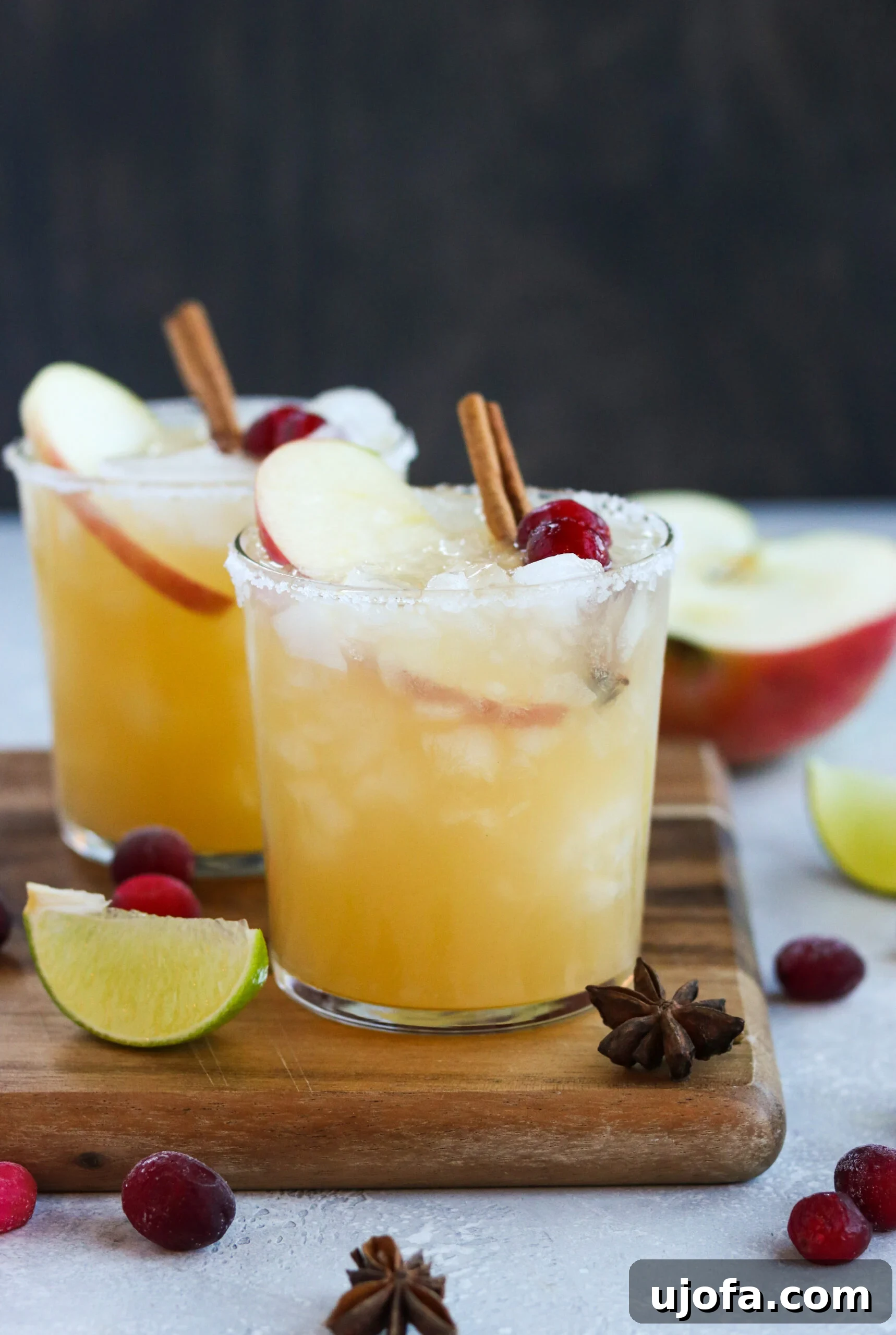 Two festive Thanksgiving cocktails beautifully arranged on a rustic wooden cutting board, inviting a sense of warmth and celebration.