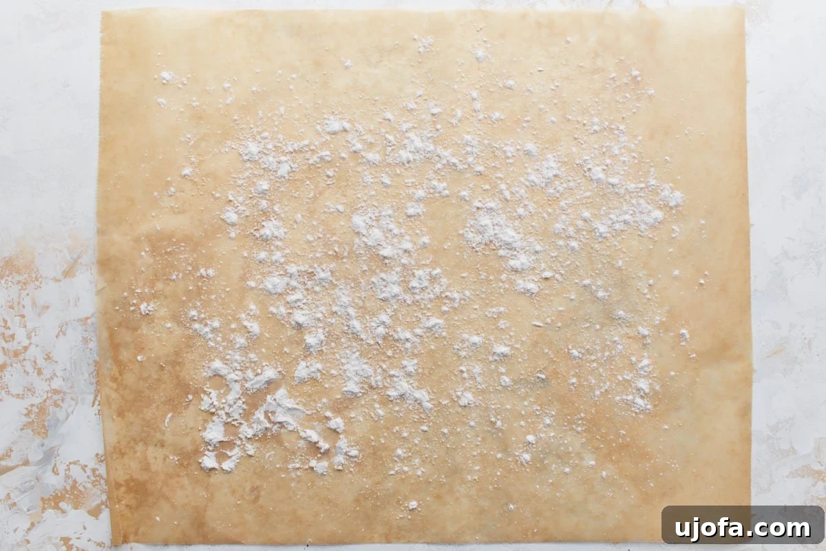 Perfect Gluten-Free Buttermilk Biscuits 8 A sheet of parchment paper lightly dusted with gluten-free flour, creating a non-stick surface for the biscuit dough.