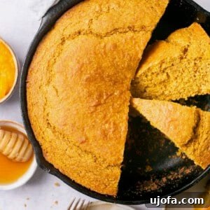 Golden-brown sweet potato cornbread, sliced and ready to serve in a cast iron pan