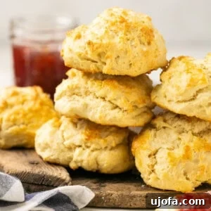 Stack of fluffy gluten-free biscuits on a cutting board with jam in the background