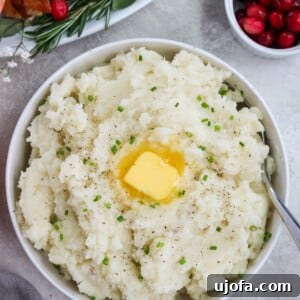 Creamy dairy-free mashed potatoes topped with vegan butter and fresh chives, served in a white bowl
