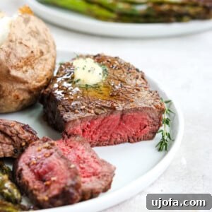 Perfectly cooked Air Fryer Filet Mignon on a white plate, topped with a dollop of herb butter