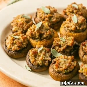 Sausage stuffed mushrooms with cream cheese, garnished with fresh sage, on a serving platter