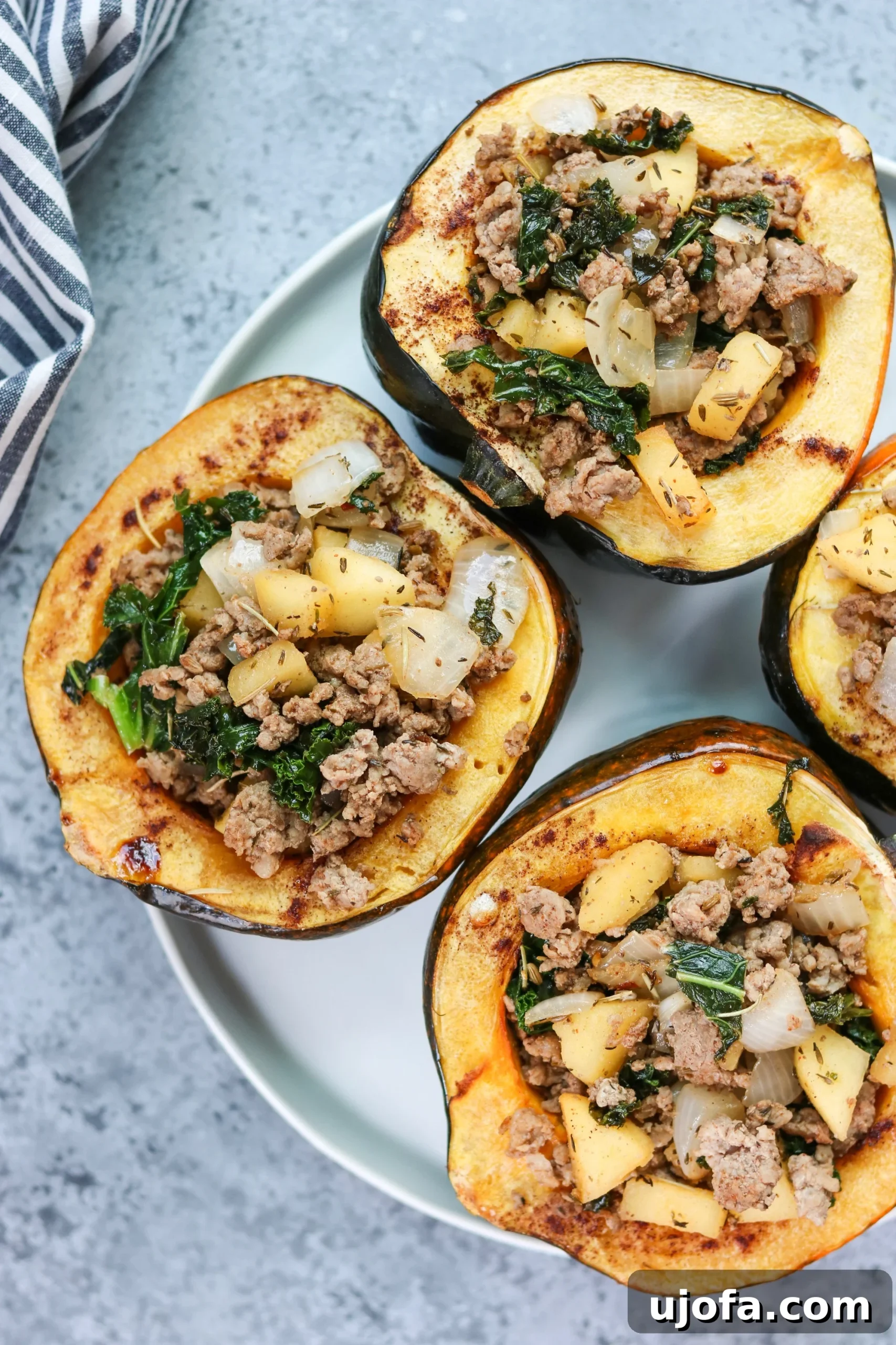 Golden Acorn Harvest Bowls 2 Two halves of Harvest Stuffed Acorn Squash on a wooden board, garnished with fresh herbs, showcasing the vibrant filling.