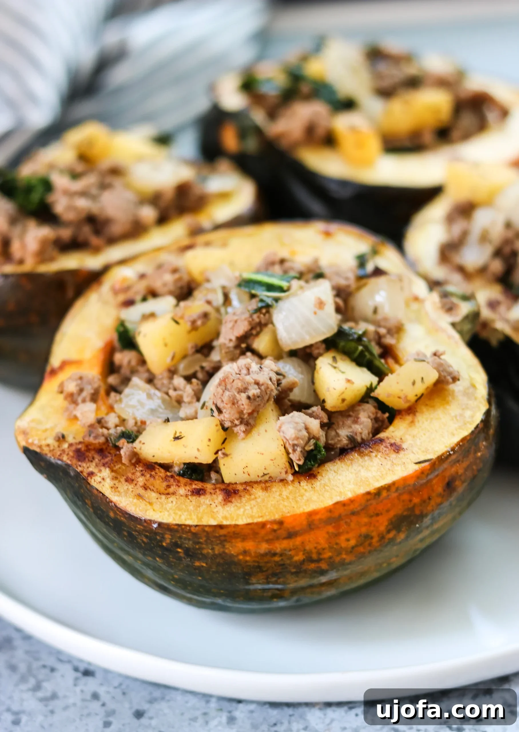 Golden Acorn Harvest Bowls 4 Raw acorn squash halves on a baking sheet, cut side up, seasoned and ready for roasting, with a focus on their deep orange flesh.