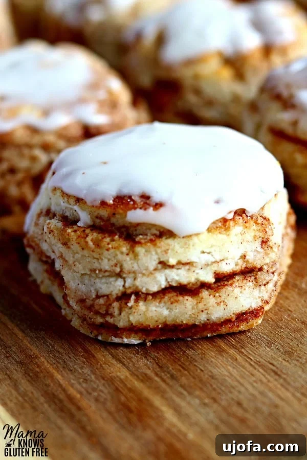 A close-up of gluten-free cinnamon biscuits generously topped with vanilla glaze, highlighting their moist texture and cinnamon swirls.