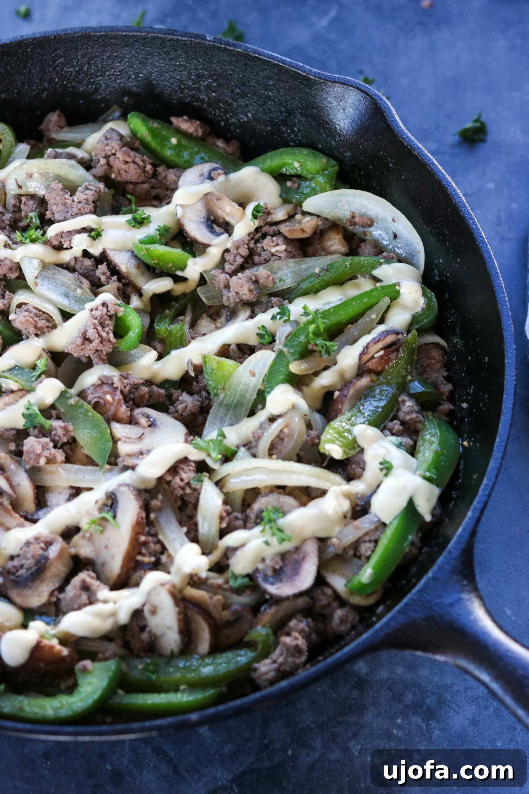 Fresh, vibrant ingredients for the Whole30 Philly Cheesesteak Skillet laid out, including ground beef, bell peppers, onions, and cashews.