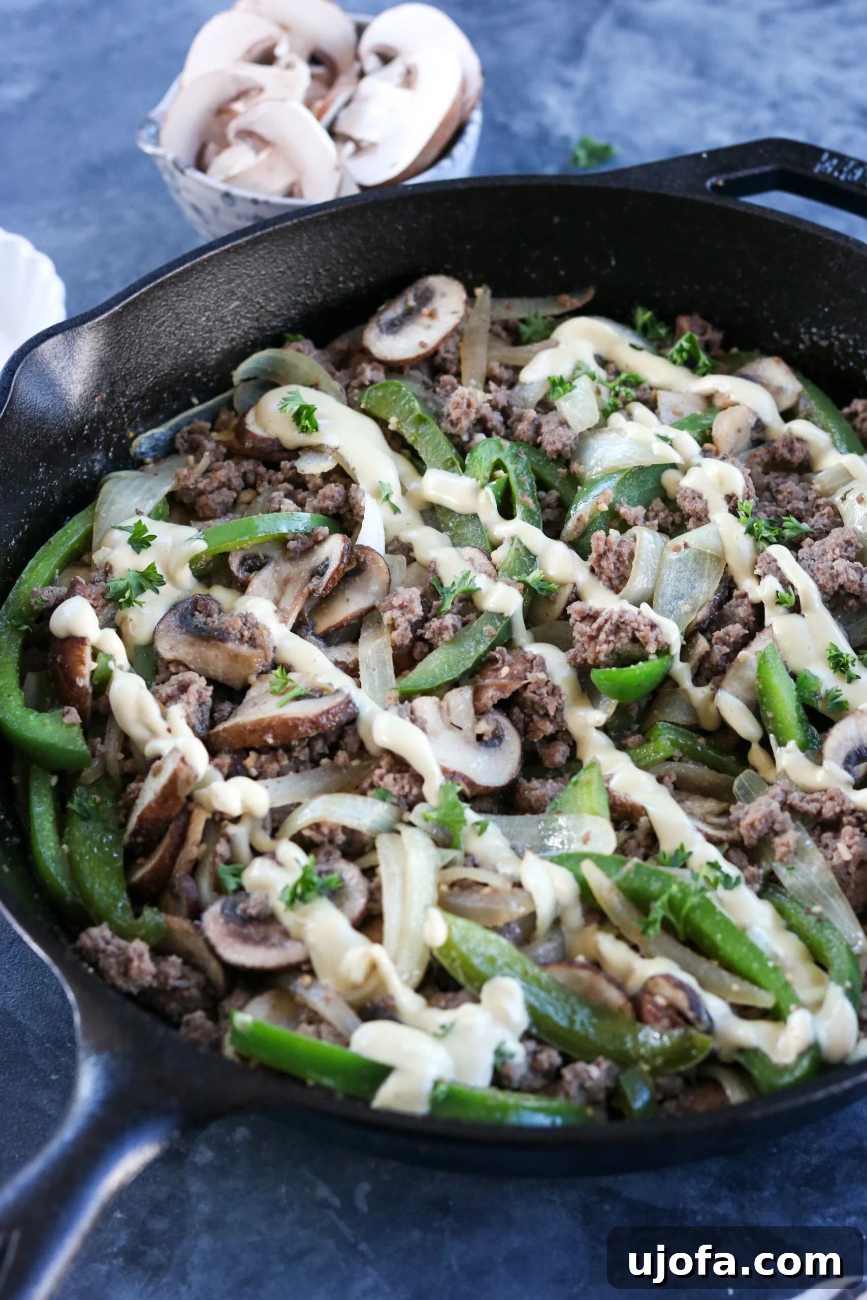A serving of the Whole30 Philly Cheesesteak Skillet, beautifully plated and drizzled with the creamy cashew cheese sauce.