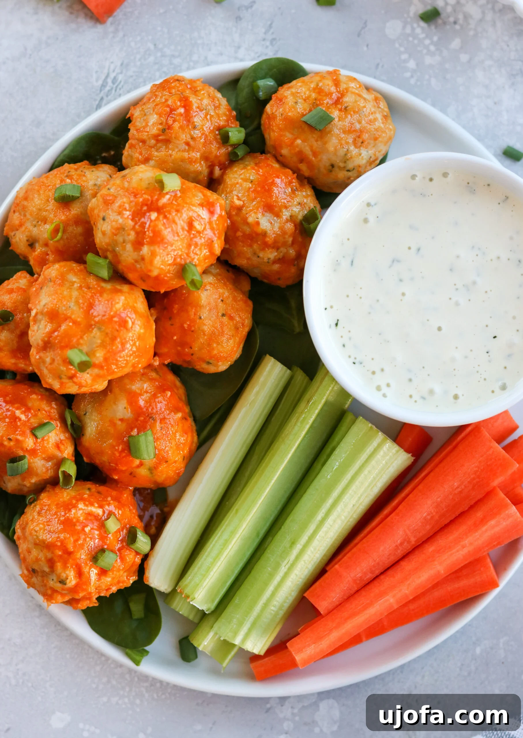 Buffalo Chicken Meatballs with a side of creamy ranch dressing, garnished with fresh herbs, perfect for game day or a healthy meal.