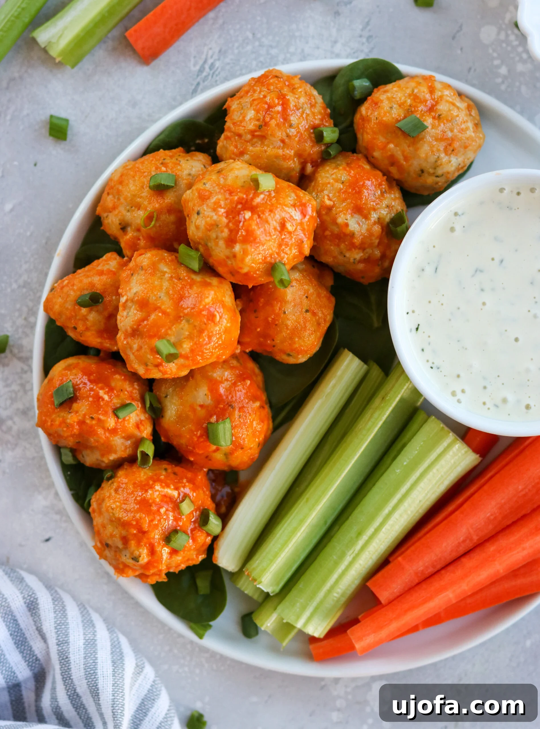 A vibrant bowl featuring gluten-free buffalo chicken meatballs, creamy avocado slices, and fresh green salad, forming a healthy and balanced meal.
