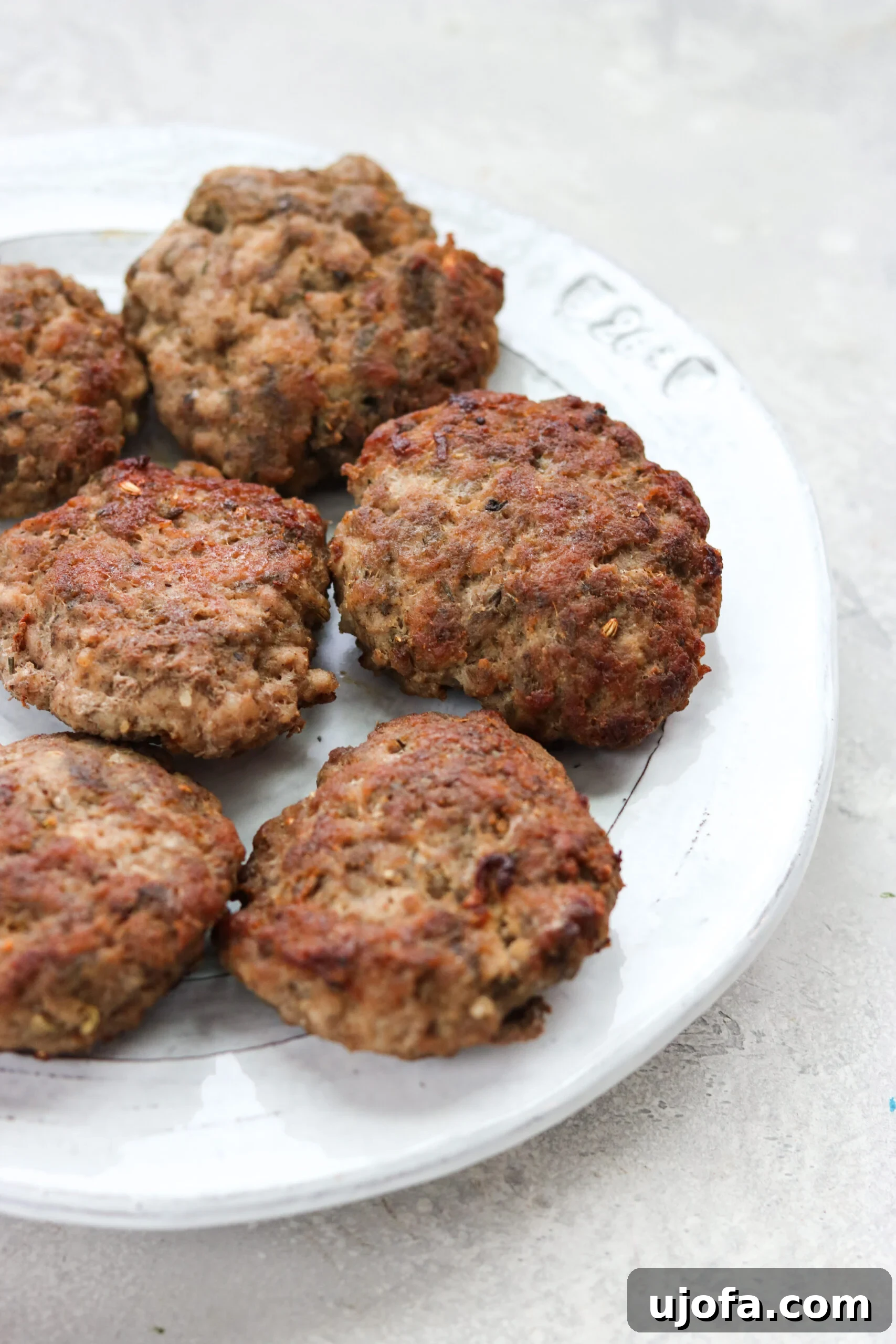 A close-up view of perfectly browned Air Fryer sausage patties resting on a plate, highlighting their appetizing texture and golden crust.