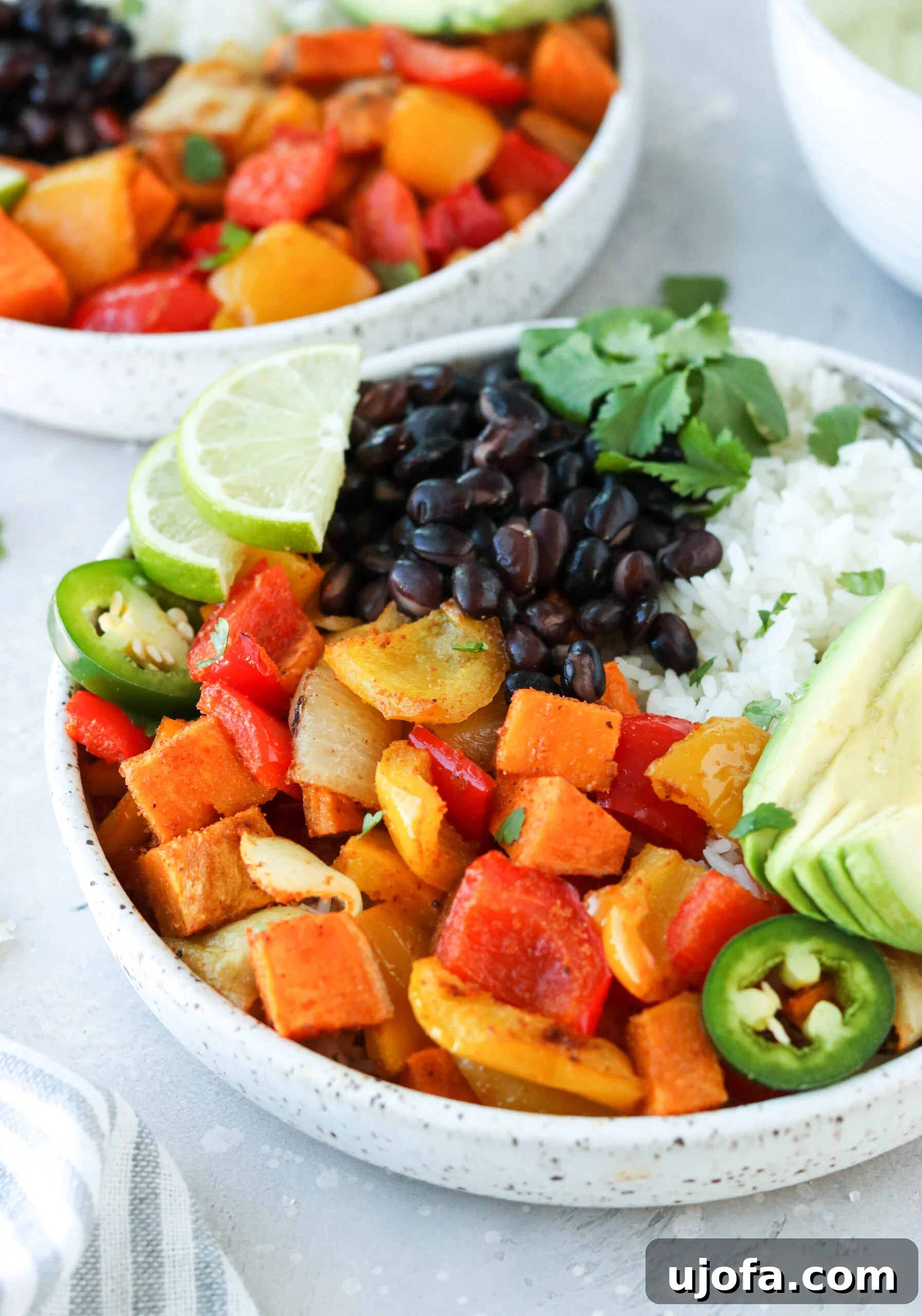 Deconstructed Burrito Bowl Elements Ready for Assembly Roasted vegetables, fluffy white rice, creamy avocado slices, and zesty lime segments artfully arranged in a bowl