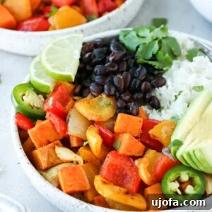 Vibrant Veggie Burrito Bowls with Creamy Avocado Drizzle 2 A close-up of a rustic wooden bowl filled with roasted vegetables, avocado slices, and lime wedges, showcasing the fresh and wholesome ingredients for building delicious burrito bowls.