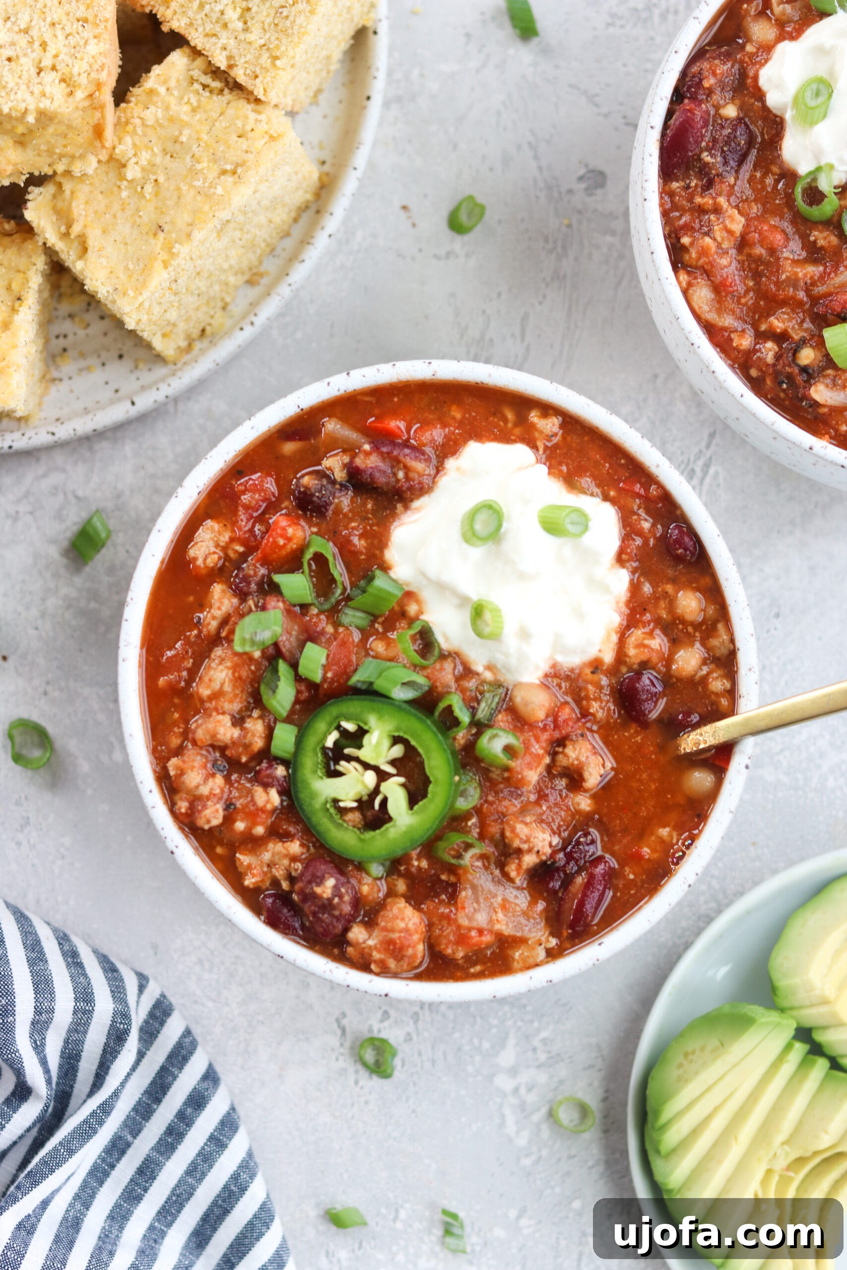 Overhead shot of a pot of slow cooker turkey chili, richly textured with ground turkey, beans, and vibrant vegetables, garnished with a sprig of cilantro.