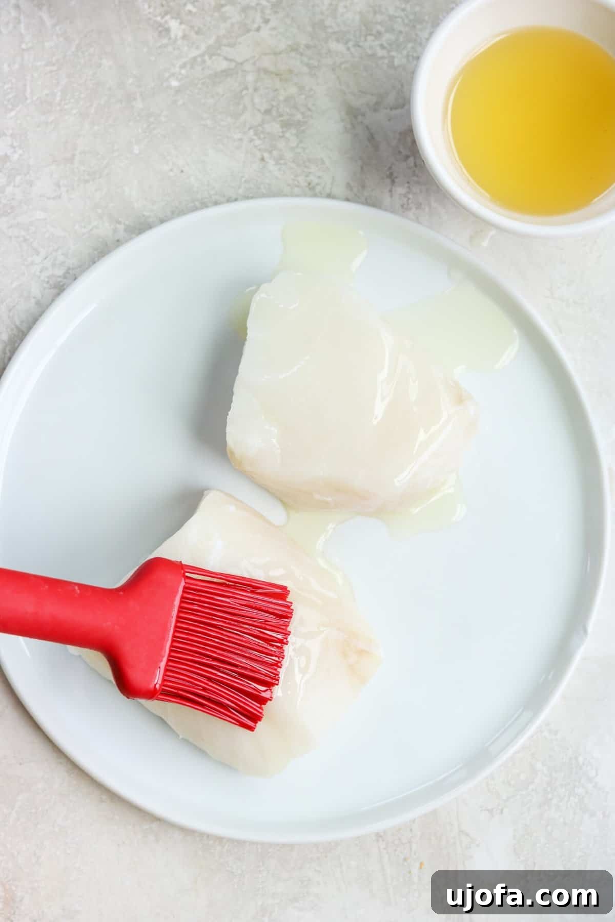20-Minute Chilean Sea Bass with Bright Lemon Caper Butter 5 A red brush applying a thin layer of oil onto sea bass fillets before seasoning.
