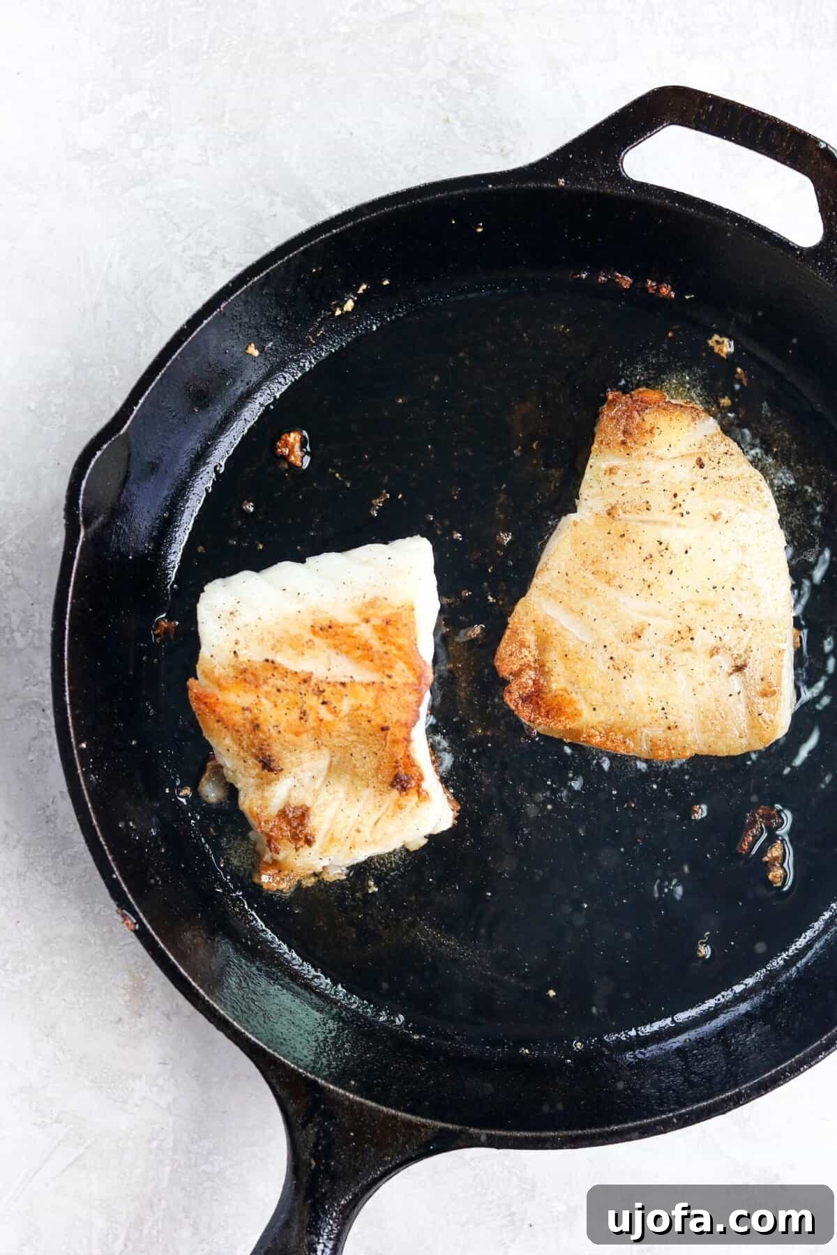 20-Minute Chilean Sea Bass with Bright Lemon Caper Butter 7 Perfectly pan-seared Chilean sea bass, golden and flaky, finishing its cooking process in a cast-iron pan.