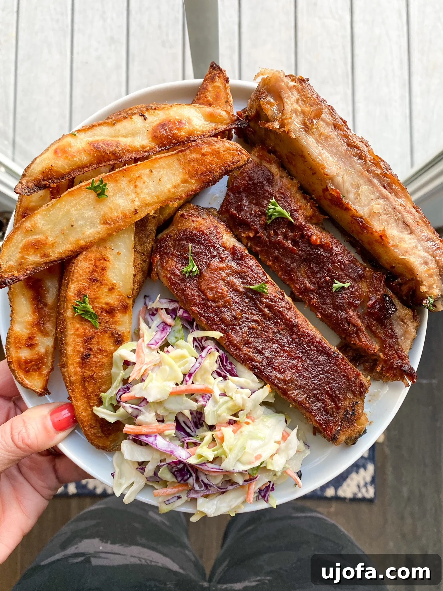 Deliciously golden and crispy potato wedges served on a pristine white plate, accompanied by perfectly grilled ribs, creating a mouth-watering meal