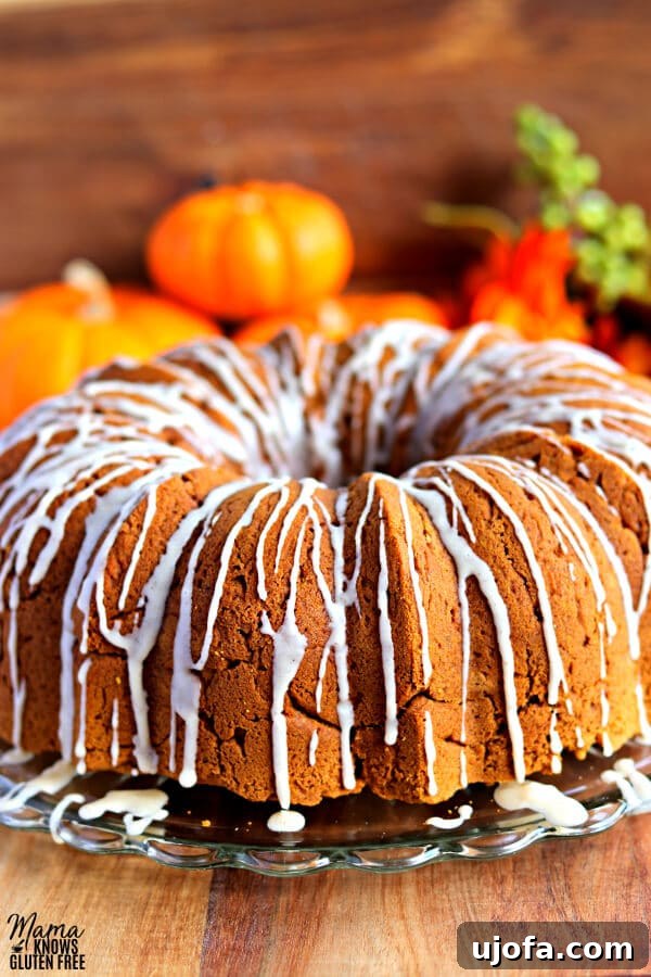 Delicious gluten-free pumpkin bundt cake, perfectly glazed, with autumn pumpkins in the background.