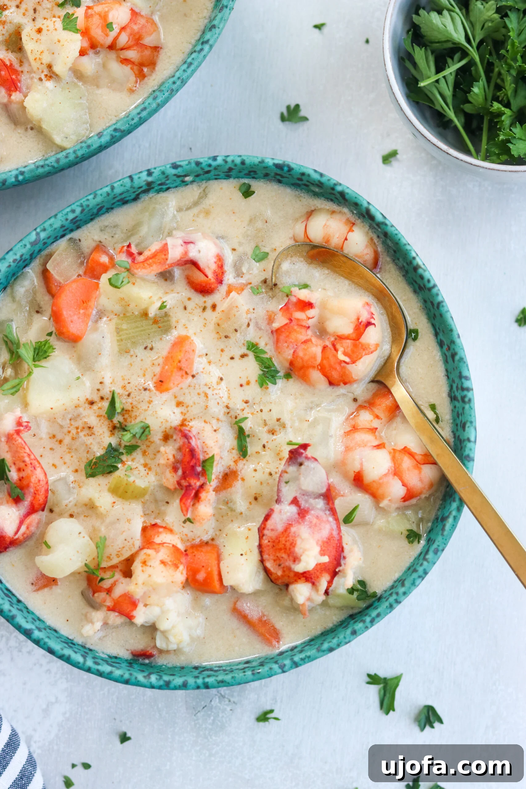 Paleo Seafood Chowder, creamy and delicious A hearty bowl of creamy Paleo Seafood Chowder, garnished with fresh herbs, served with a golden spoon.
