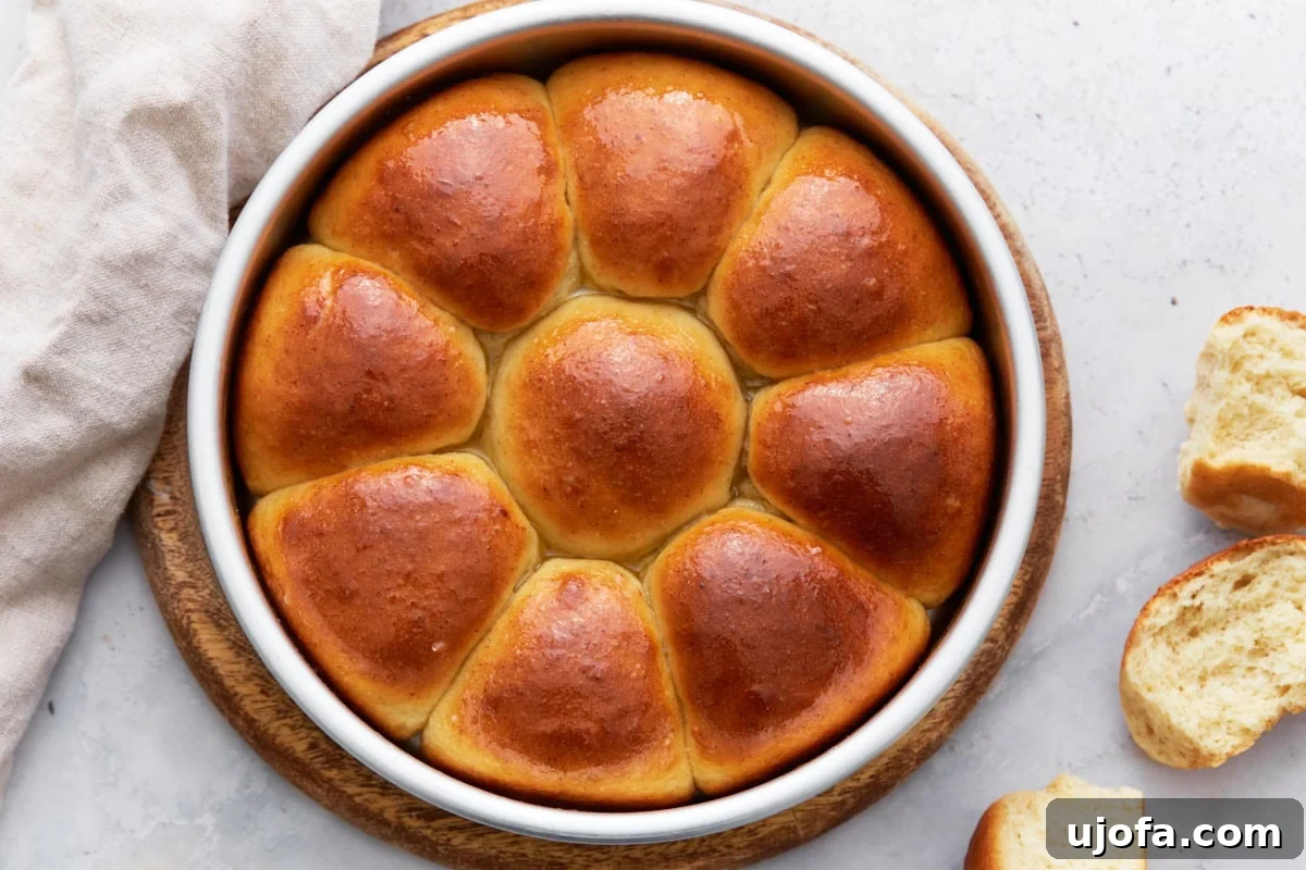 Freshly baked gluten-free dinner rolls being brushed with melted butter