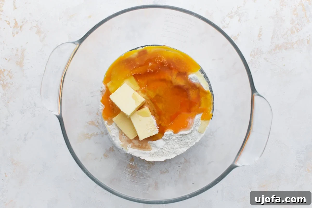 Pouring warm milk into a bowl with dry ingredients and yeast for gluten-free rolls