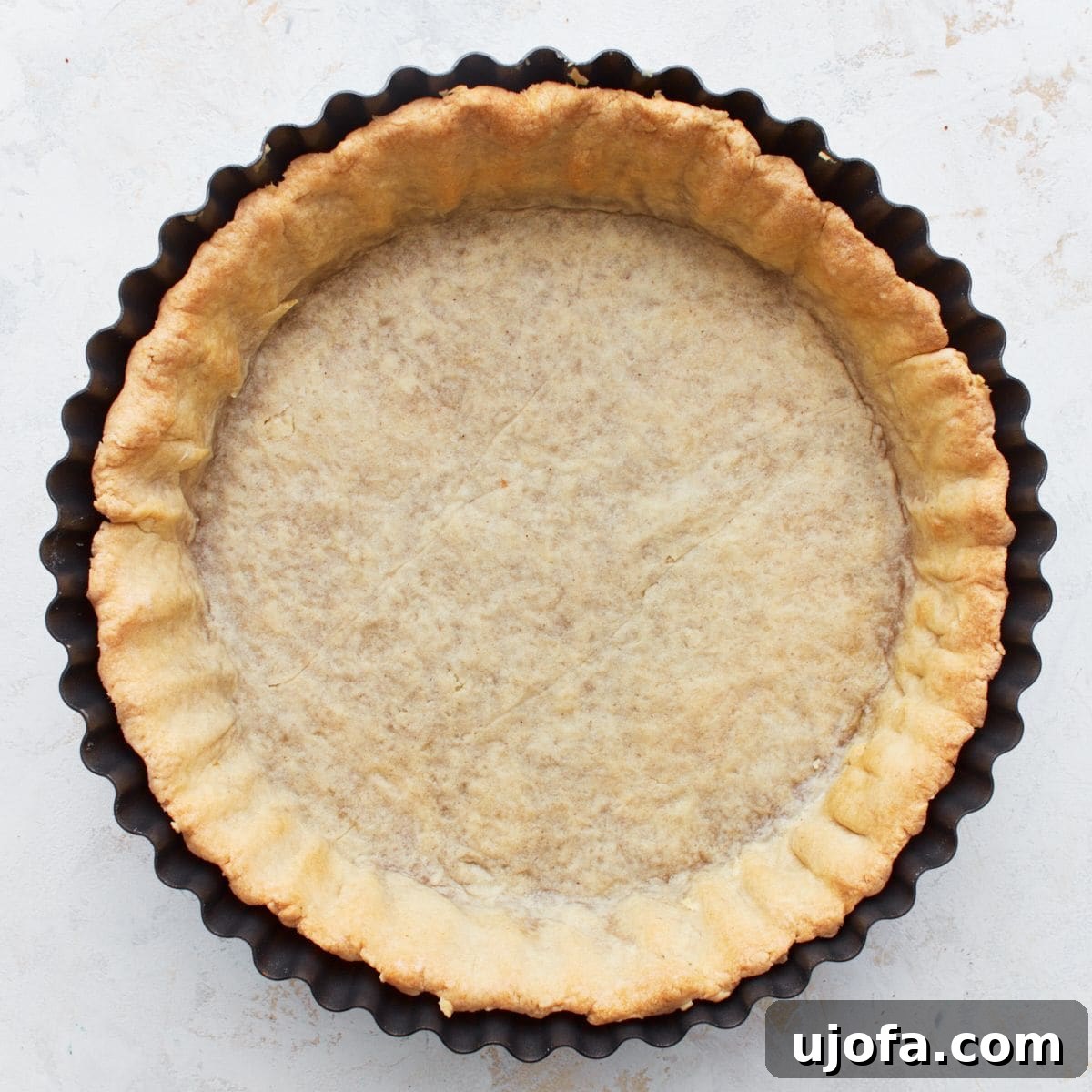 Overhead view of a perfectly golden-brown gluten-free pie crust in a pie pan, ready for filling.