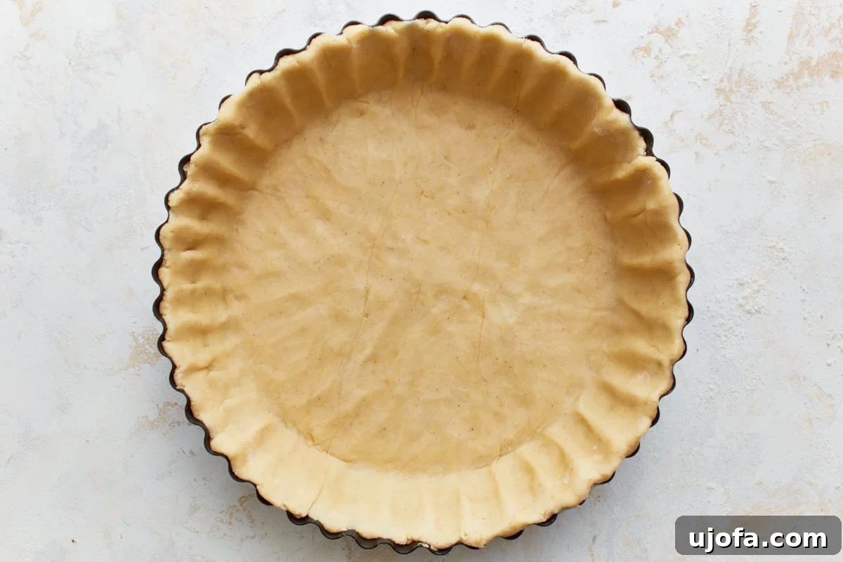 An unbaked gluten-free pie crust expertly fitted into a greased pie pan, with crimped edges.