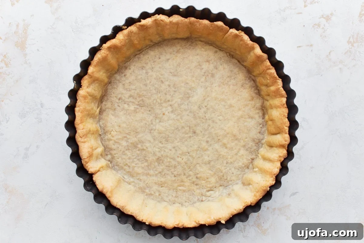 A freshly baked, golden-brown gluten-free pie crust sitting in a pie pan on a cooling rack.