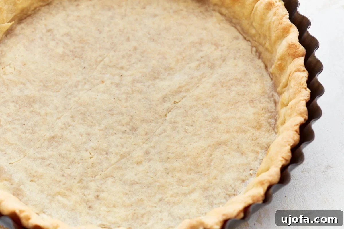 A beautifully fluted, unbaked gluten-free pie crust in a metal pie pan, ready for filling.