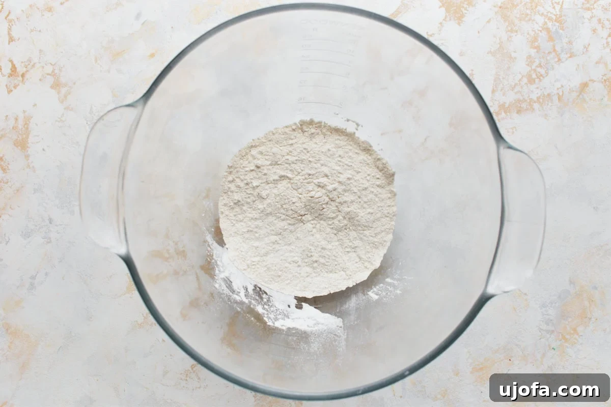 Gluten-free flour and other dry ingredients in a glass mixing bowl, with chunks of chilled butter and shortening ready to be added.