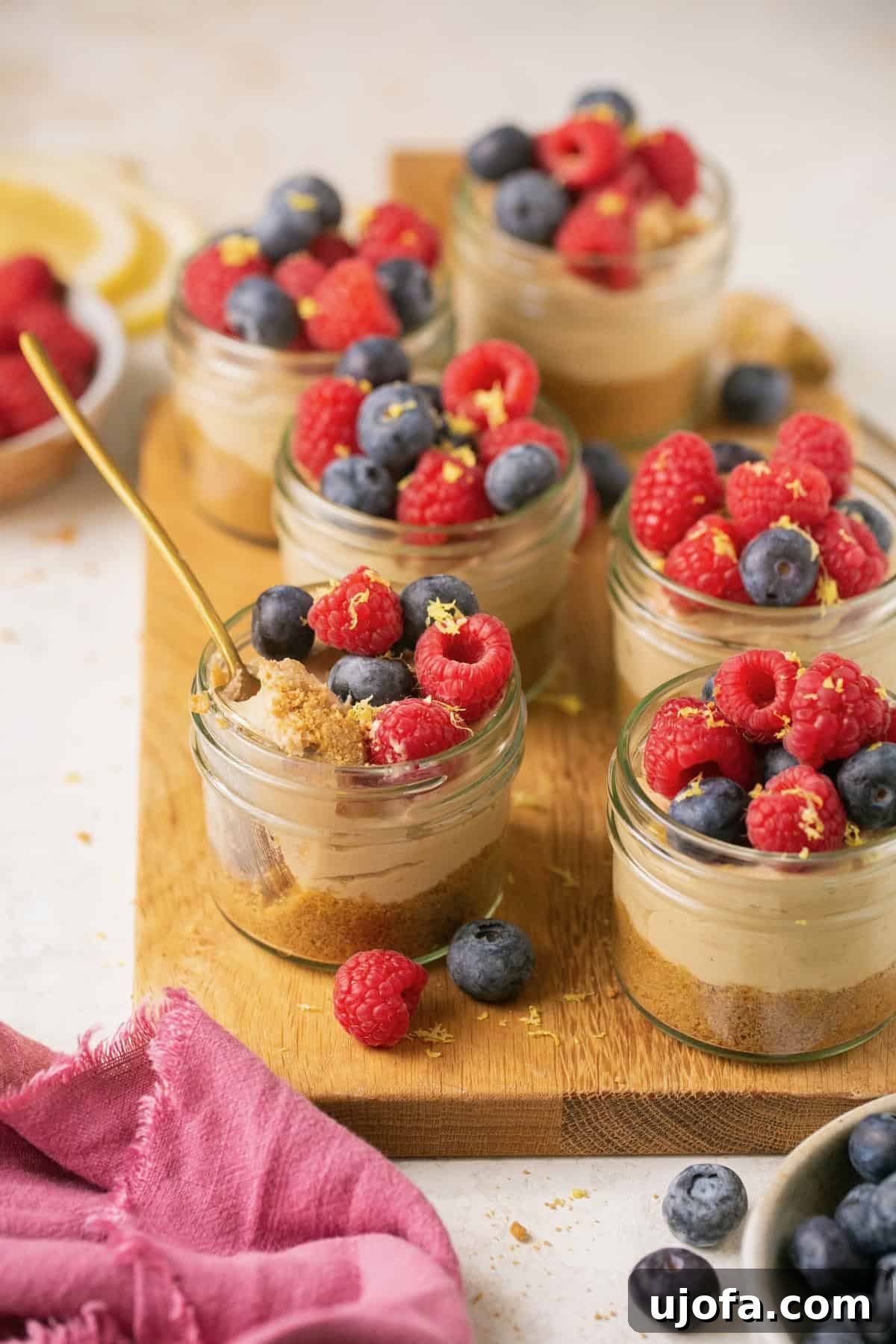 Decadent Gluten-Free No-Bake Cheesecake Cups 2 jars of mini cheesecakes topped with vibrant fresh berries and whipped cream