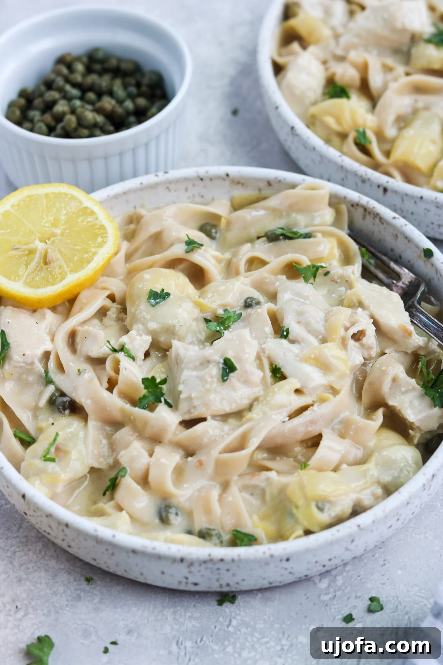 Gluten-free pasta with creamy lemon artichoke chicken, garnished with fresh herbs