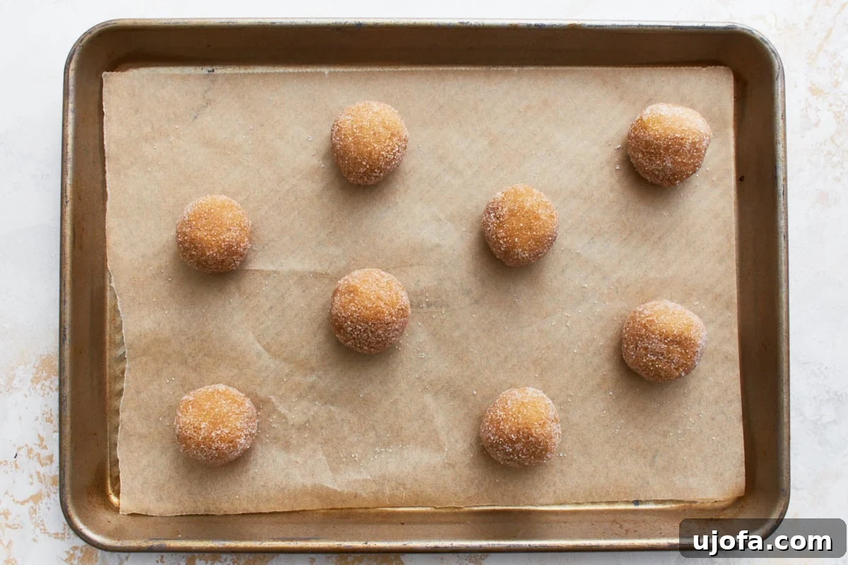 A close-up of gluten-free peanut butter dough balls, rolled and ready to be baked, placed on a light textured surface.
