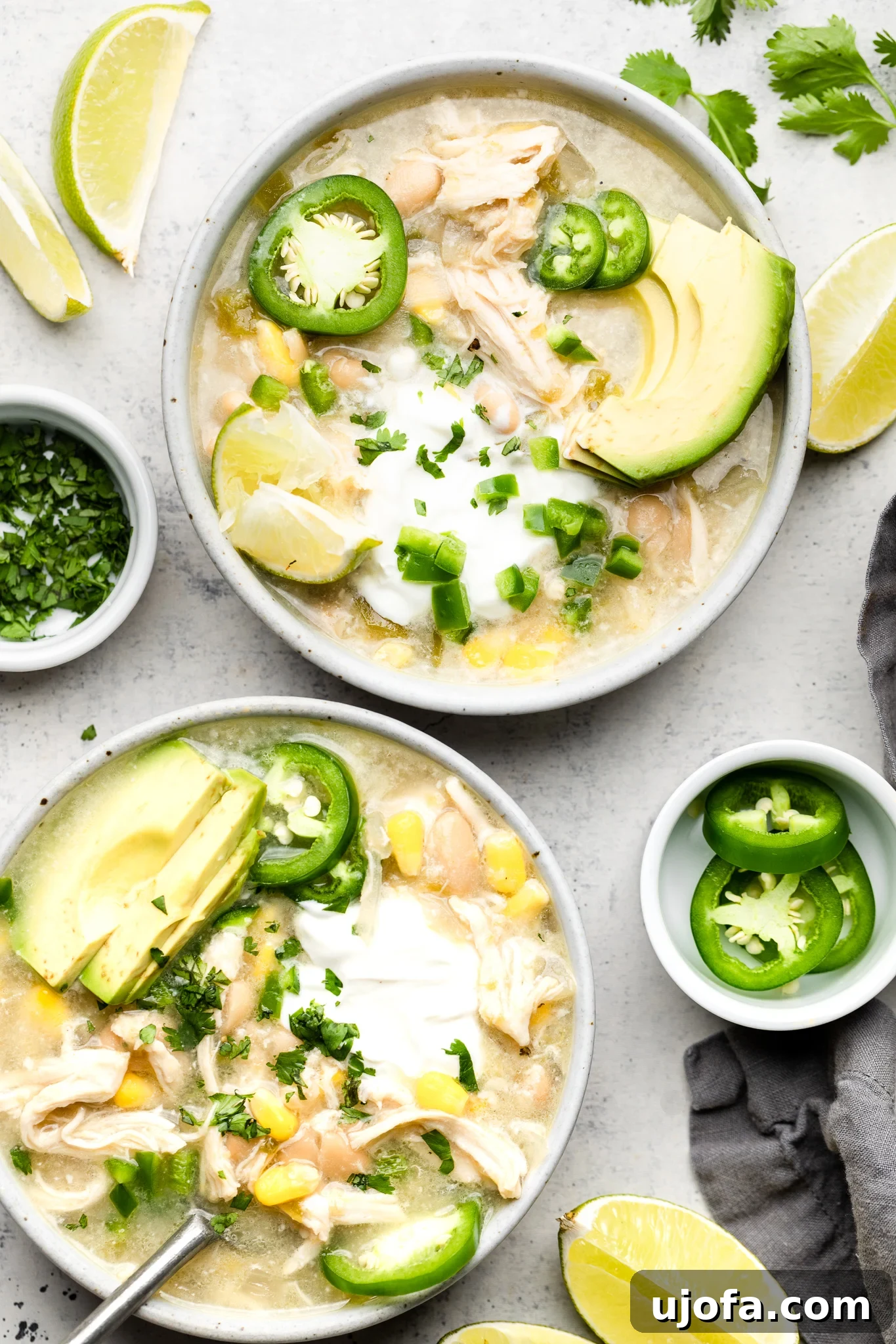 Effortless Velvety Green Chicken Chili Soup 5 Two bowls of green chicken chili soup, richly topped with various fresh ingredients, ready for serving.
