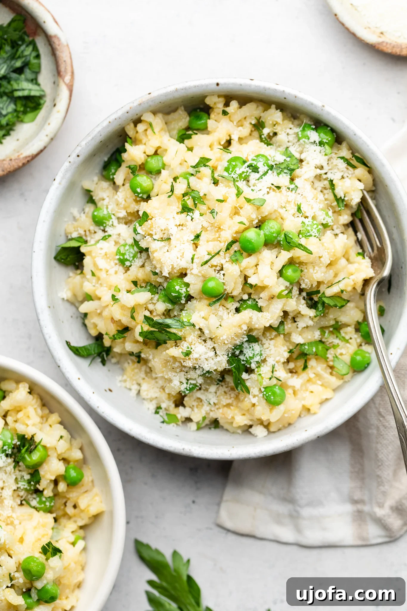 bowl of risotto with peas topped with parsley and parmesan cheese