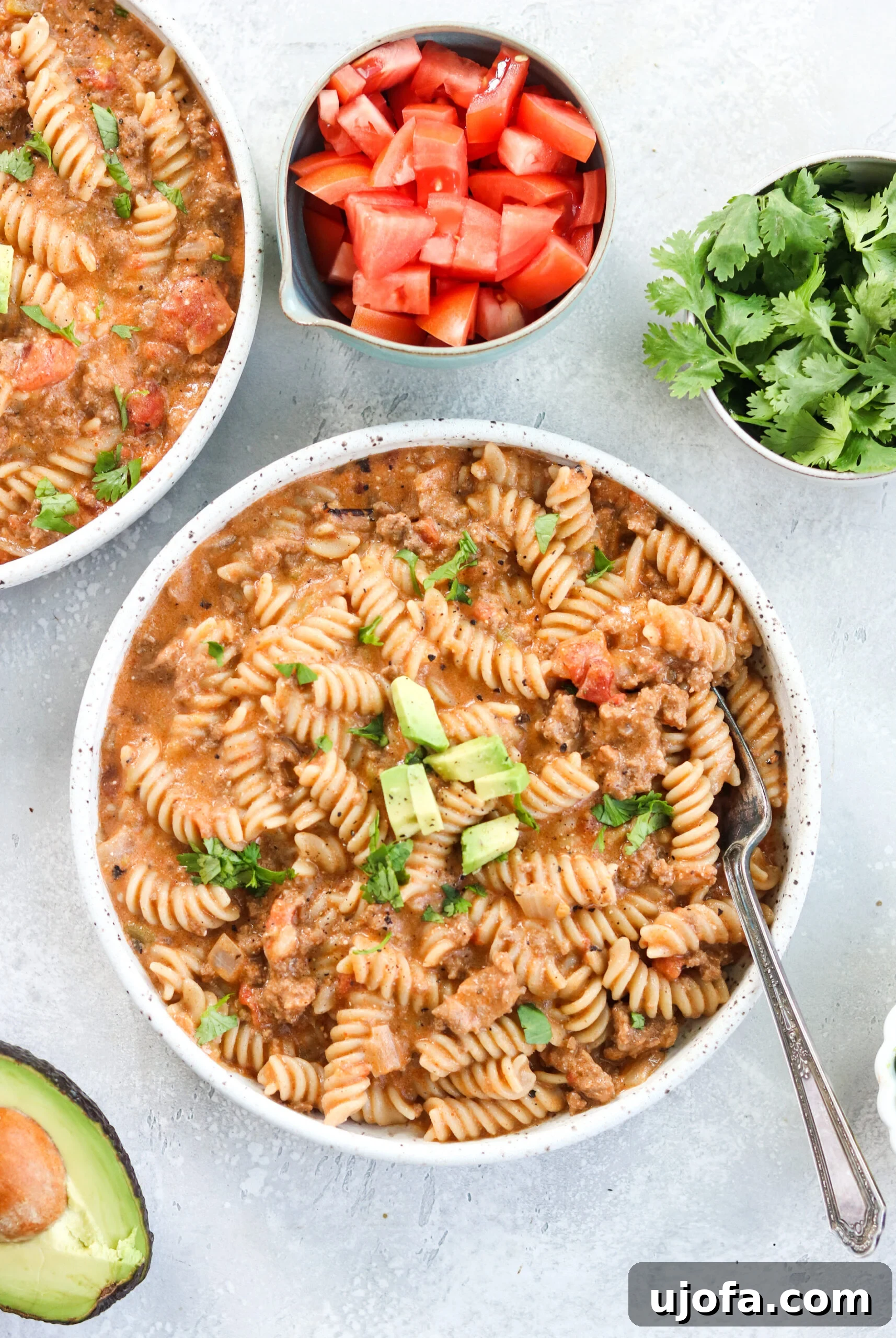 Overhead view of a prepared Instant Pot Taco Pasta with fresh avocado, cherry tomatoes, and mint sprigs as garnishes
