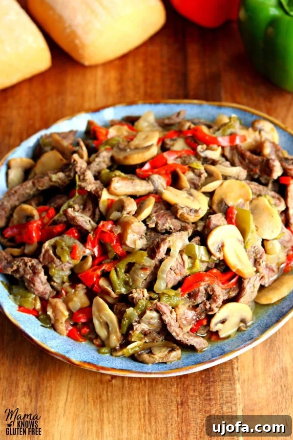 Fork-Tender Instant Pot Steak Sandwiches 5 A blue plate full of cooked sliced steak, bell peppers, mushrooms, and ions, ready to be served.