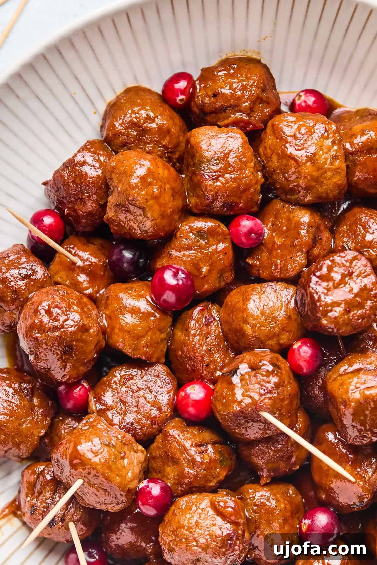 cranberry jalapeno chicken meatballs in a white bowl with whole cranberries scattered throughout