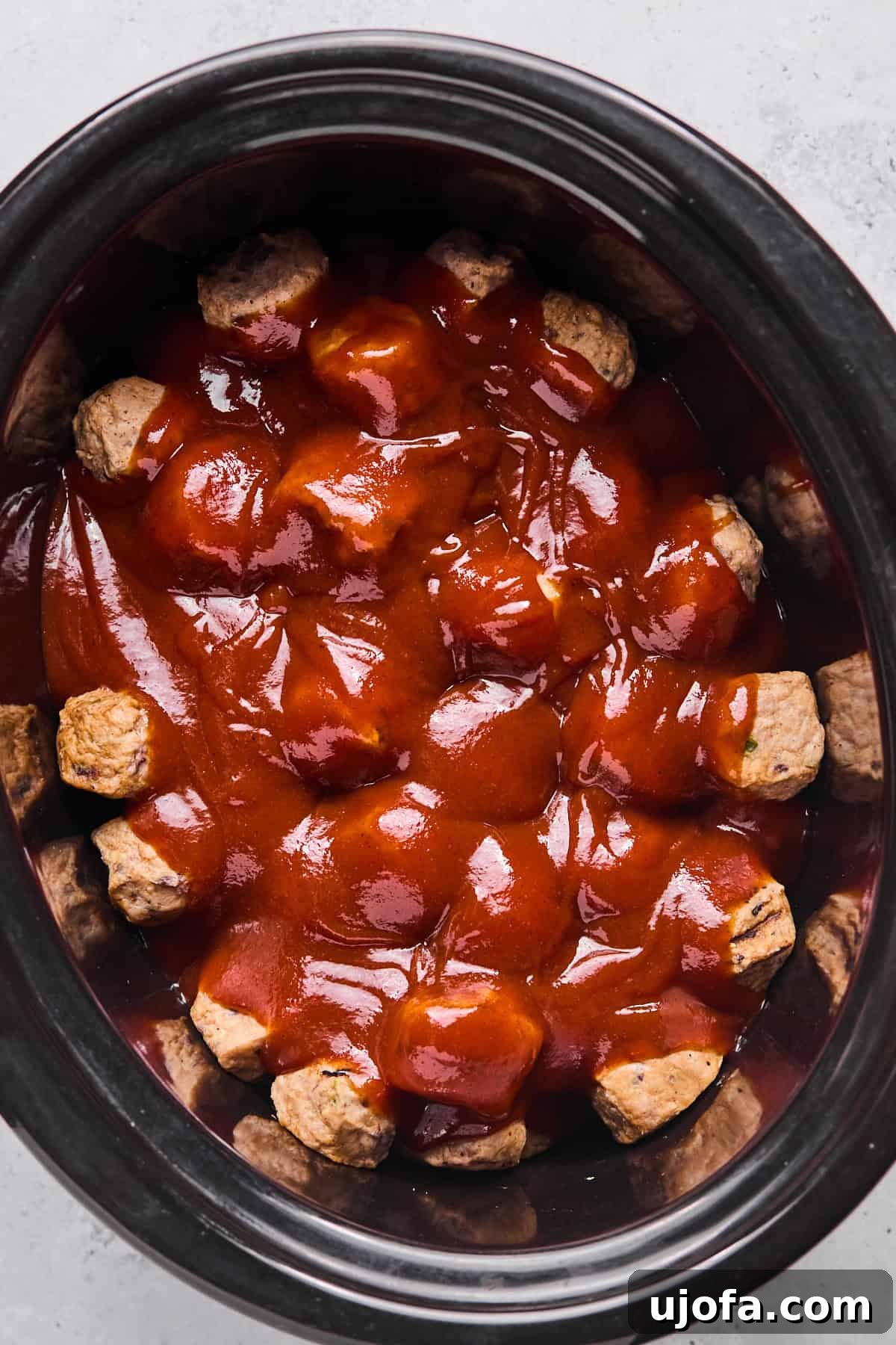bbq sauce on top of meatballs in a crockpot 