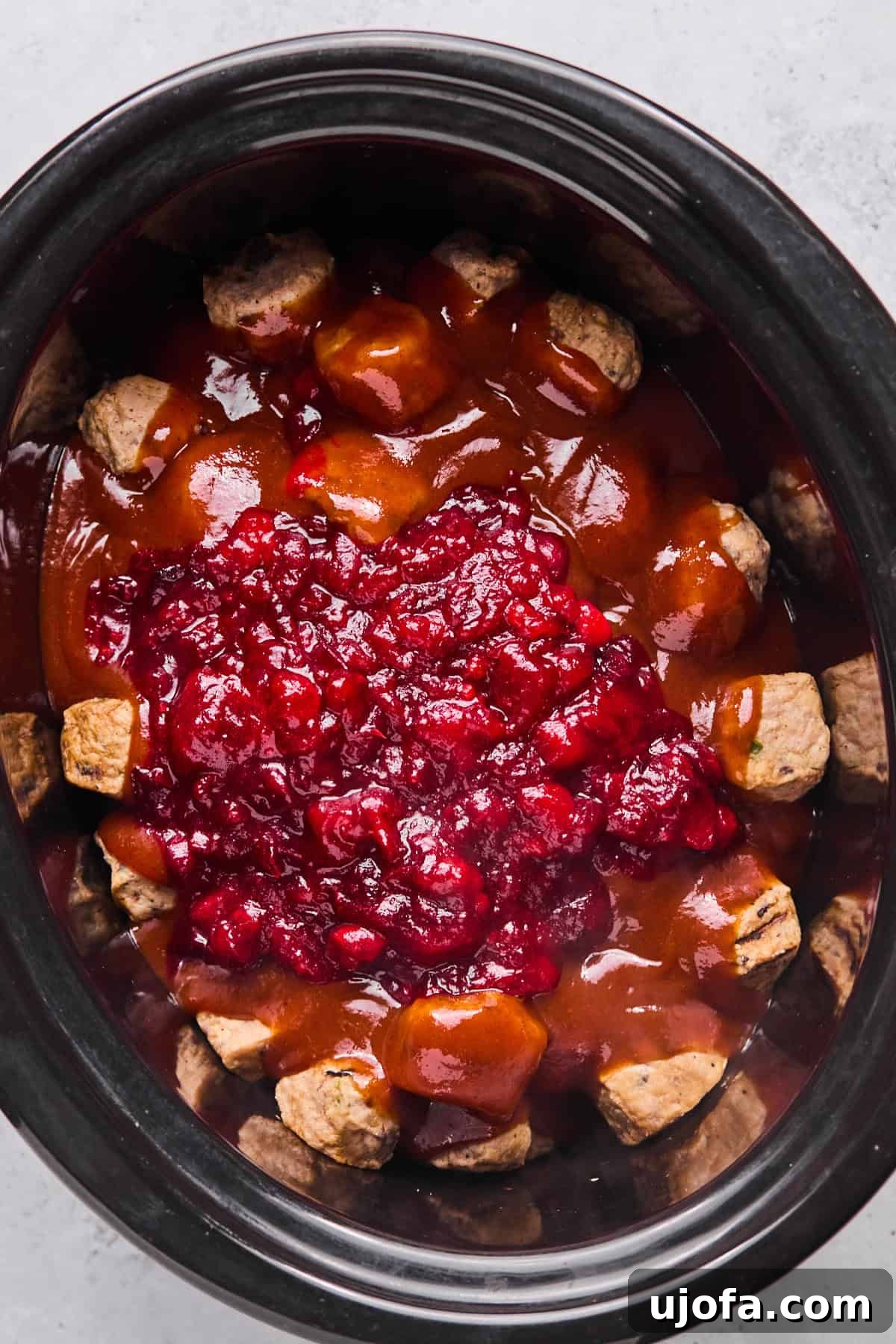 cranberry sauce poured on top of the bbq sauce and meatballs in the slow cooker