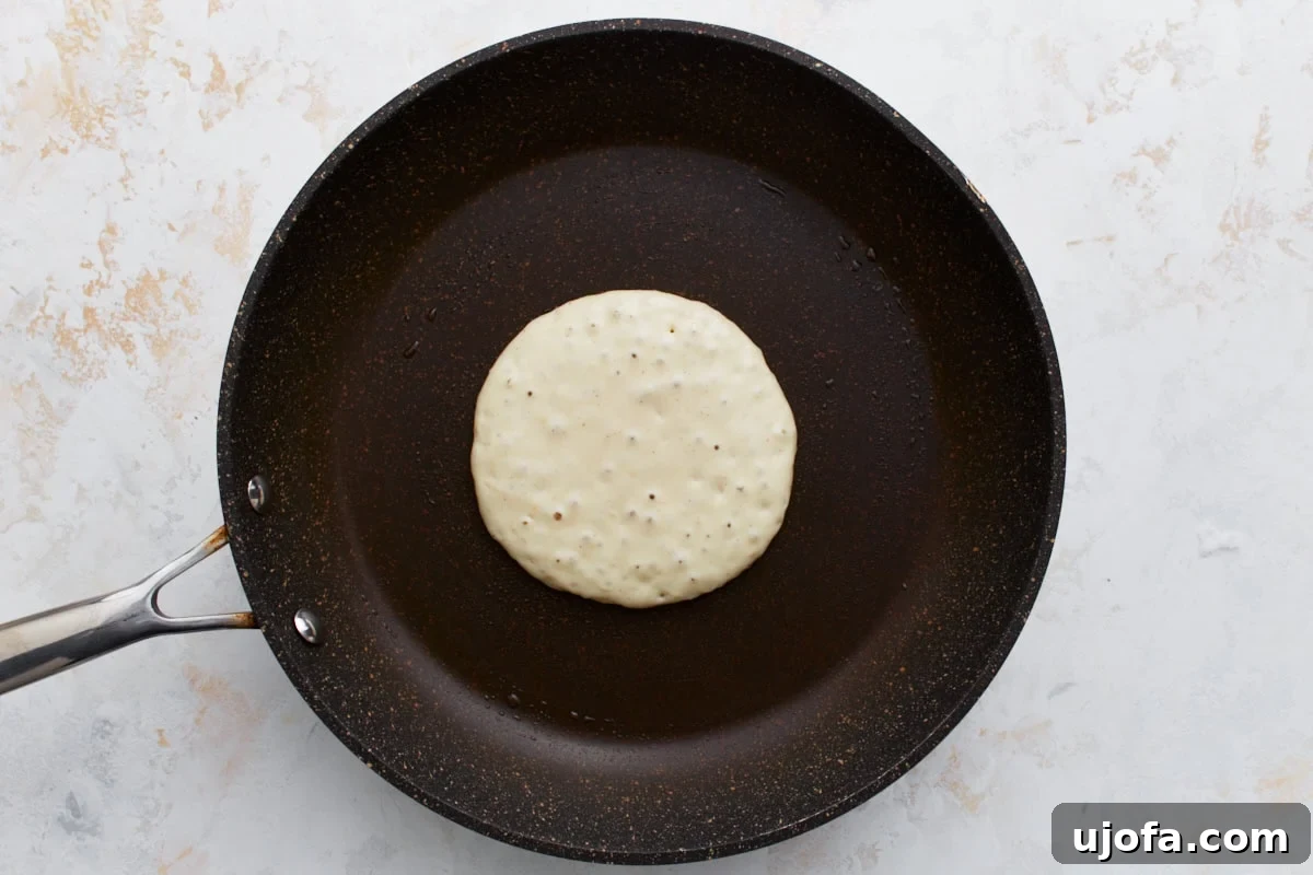 Foolproof Gluten-Free Pancakes 9 A pancake on the skillet showing small bubbles forming on the surface, indicating it’s ready to flip.