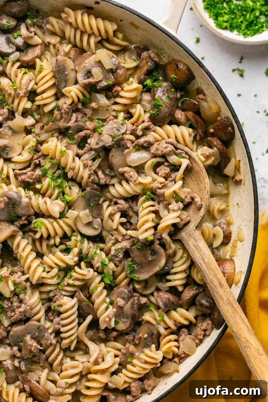A close-up of gluten-free hamburger helper stroganoff in a pot with a wooden spoon, ready to serve.