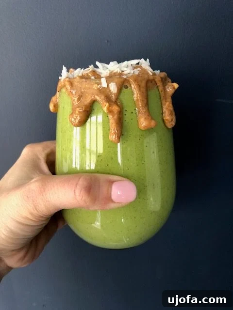 Rainforest Radiance Smoothie 2 Vibrant Tropical Green Smoothie in a glass, garnished with fresh fruit and coconut shreds.