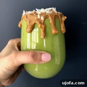 Close-up of a refreshing green smoothie in a glass, with tropical fruit garnish.