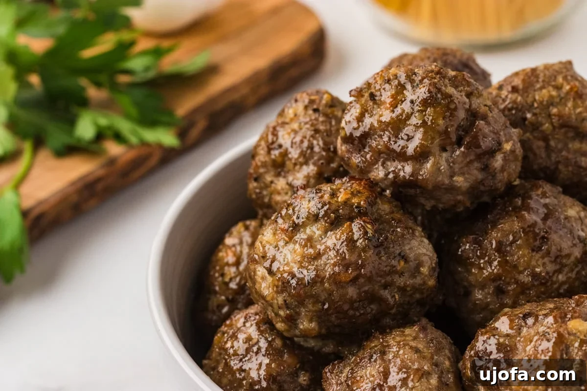 Glossy, golden-brown gluten-free meatballs stacked in a white bowl, ready to serve.