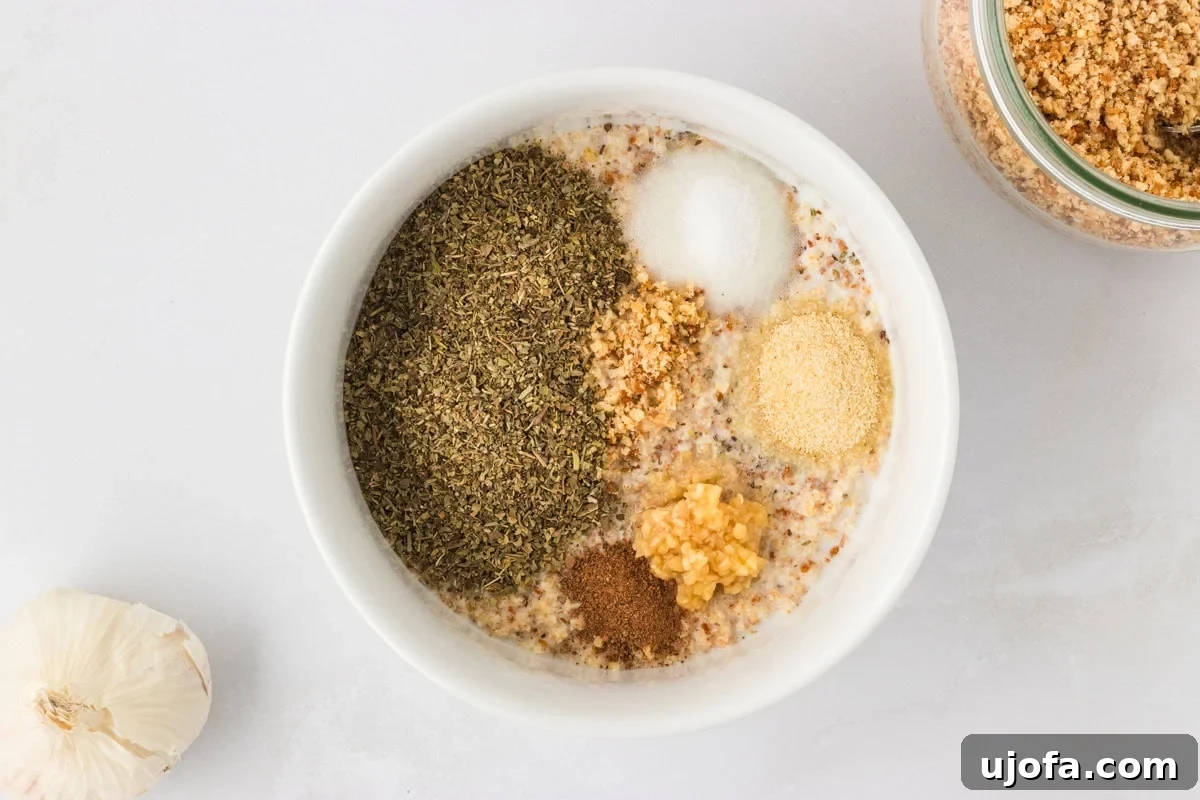 White bowl filled with gluten-free breadcrumbs, dried Italian herbs, garlic, onion powder, and other seasonings for the meatball mixture.