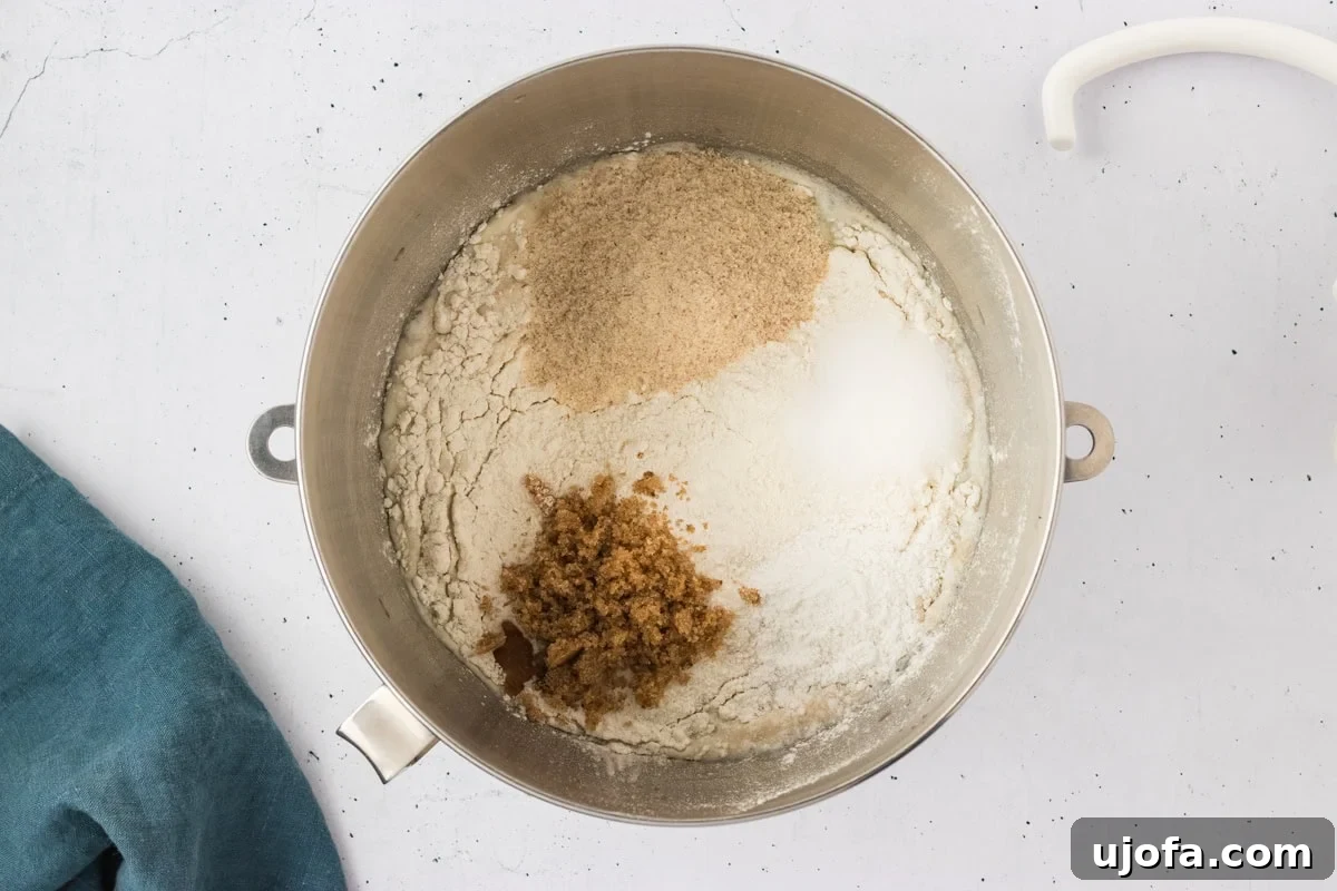 A mixing bowl with gluten-free flour, psyllium husk, brown sugar, salt, and baking powder added on top of the frothy yeast mixture.