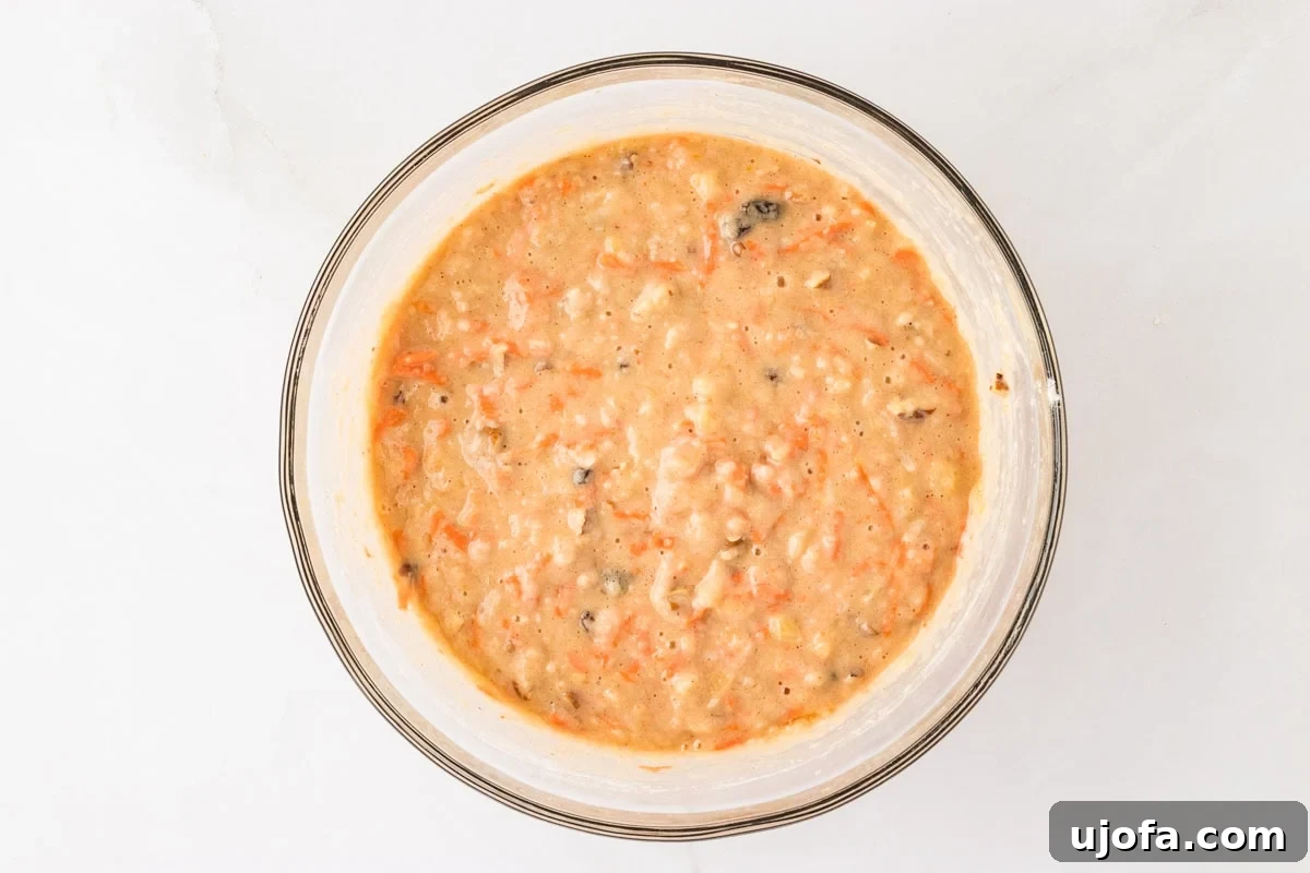A mixing bowl with fully mixed gluten-free carrot cake batter, smooth and ready to be poured into cake pans.