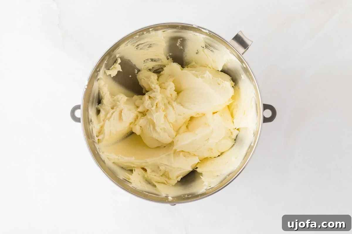 A mixing bowl of whipped cream cheese and butter, showing the smooth and fluffy texture of the frosting base.