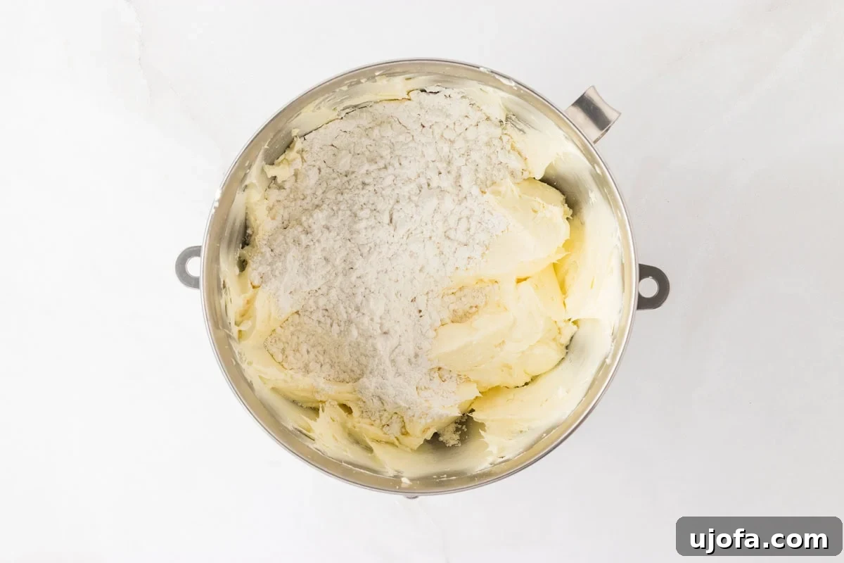 A mixing bowl with cream cheese frosting and a dusting of powdered sugar added on top, ready to be combined.